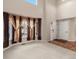 Open living room with a soaring ceiling, large windows dressed with decorative curtains, and hardwood flooring at 11254 Oakland Dr, Commerce City, CO 80640