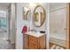 Bathroom view featuring a wood cabinet, oval mirror, and a glimpse of the bathtub and toilet at 3295 S Estes St, Lakewood, CO 80227