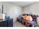 Cozy bedroom with a daybed covered in decorative pillows and a blanket, featuring a nearby table and gaming console at 3295 S Estes St, Lakewood, CO 80227