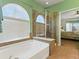 A bathtub with a window and shower, and a door that leads to the bedroom is featured at 22647 Hopewell Ave, Parker, CO 80138