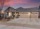 Inviting brick home with a covered front porch and two-car garage illuminated at twilight at 22647 Hopewell Ave, Parker, CO 80138