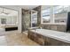 Relaxing primary bathroom with soaking tub, glass shower, large windows, and tile surround at 26404 E Caley Dr, Aurora, CO 80016