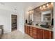 Bathroom featuring dual sinks, granite countertops, wood-look accent wall, and custom closet at 26404 E Caley Dr, Aurora, CO 80016