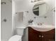 Cozy bathroom featuring a white toilet, a wooden vanity with a round mirror, and a shower with brushed nickel fixtures at 1451 S Quitman St, Denver, CO 80219