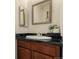 Traditional bathroom vanity with black countertop, oval sink, and decorative mirror create a cozy space at 1451 S Quitman St, Denver, CO 80219