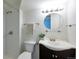 Well-lit bathroom features a vanity sink, modern fixtures, and a shower with glass shelves at 1451 S Quitman St, Denver, CO 80219