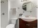 Bright bathroom featuring a round mirror, updated vanity, toilet, and modern fixtures at 1451 S Quitman St, Denver, CO 80219