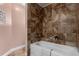 Bathroom featuring neutral tile, and a soaking tub with shower head at 1451 S Quitman St, Denver, CO 80219