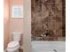 Bathroom featuring a bathtub with tiled walls, a toilet, and a small window letting in natural light at 1451 S Quitman St, Denver, CO 80219