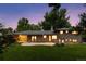 Dusk shot of the backyard and patio featuring the brick home and lush lawn at 3190 S Detroit St, Denver, CO 80210