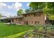 Backyard with brick home, covered patio, lush green lawn, and flower bed at 3190 S Detroit St, Denver, CO 80210