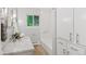 Bathroom featuring a white marble vanity, soaking tub, neutral-toned tile floor, and built-in storage at 3190 S Detroit St, Denver, CO 80210