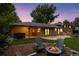 Evening shot of the backyard featuring a hot tub, a fire pit, and covered patio at 3190 S Detroit St, Denver, CO 80210