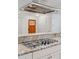 Close-up of granite countertop with stove cooktop and modern stainless steel range hood at 3190 S Detroit St, Denver, CO 80210