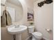 Neat powder room featuring classic pedestal sink, commode, and round mirror at 22560 E Rowland Dr, Aurora, CO 80016