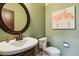 Charming powder room featuring unique wall art, classic fixtures, and a decorative round mirror at 860 Quintana Ln, Erie, CO 80516