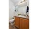 Bathroom featuring a white toilet, wood vanity, large mirror and window with blinds at 10223 Vine Ct, Thornton, CO 80229
