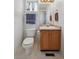 Cozy bathroom features a toilet, small vanity and mirror, a tiled floor and a sunny window at 10223 Vine Ct, Thornton, CO 80229