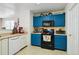 Kitchen boasting blue cabinets with black hardware, white appliances and tile flooring at 10223 Vine Ct, Thornton, CO 80229