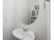 Small powder room with pedestal sink, rounded mirror, and neutral decor, offering a functional and stylish space at 203 S Oak Hill St, Aurora, CO 80018
