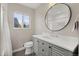 Bright bathroom with a gray vanity, round mirror, toilet, and window at 2999 S Adams St, Denver, CO 80210