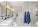 Bright bathroom with a double sink vanity, gold light fixtures, and glass enclosed shower with marble tile at 2999 S Adams St, Denver, CO 80210