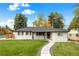 Well-manicured lawn and charming white brick home with a dark roof at 2999 S Adams St, Denver, CO 80210