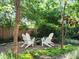 A cozy backyard gathering space with white Adirondack chairs, a fire pit, and lush landscaping all around at 1985 Union St, Lakewood, CO 80215