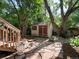 An outdoor backyard shed with red doors sits on a stone paver foundation between mature trees at 1985 Union St, Lakewood, CO 80215