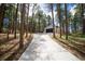Long concrete driveway leads to a modern detached garage, surrounded by tall trees at 14546 Pine View Rd, Larkspur, CO 80118