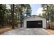 Detached garage with black garage door and white siding, nestled among trees at 14546 Pine View Rd, Larkspur, CO 80118