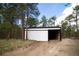 Newer outbuilding, possibly a shed, with a white facade, black trim and natural surroundings at 14546 Pine View Rd, Larkspur, CO 80118