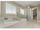 Bright bathroom with a soaking tub, glass shower, neutral tile, and a view of walk-in closet at 7734 Blue Water Dr, Castle Rock, CO 80108