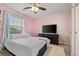 A comfortable bedroom featuring pink walls, a ceiling fan, and a large window for natural light at 7734 Blue Water Dr, Castle Rock, CO 80108