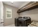 A functional laundry room with modern black appliances, shelving, and a window for natural light at 7734 Blue Water Dr, Castle Rock, CO 80108