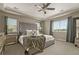 Luxurious primary bedroom featuring a tufted headboard, tray ceiling, plush carpet, and large windows at 7734 Blue Water Dr, Castle Rock, CO 80108