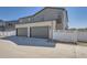 Modern two-car garage featuring gray doors and stylish brickwork on a home with gray siding and a white fence at 1294 S Algonquian St, Aurora, CO 80018