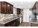 Well-lit kitchen with dark cabinets, stone backsplash, granite countertops, and stainless steel appliances at 8757 Estes Ct, Arvada, CO 80005