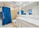 Clean bathroom with white vanity, large mirror, shower with blue curtain, and tiled floor at 3832 S Quebec St, Denver, CO 80237