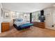 Bedroom with a bed, bench, carpet, windows with dark curtains, and wooden dressers at 3832 S Quebec St, Denver, CO 80237