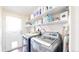 Laundry room with modern washer and dryer, complemented by white storage shelves at 66095 E Kettle Pl, Byers, CO 80103