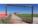Scenic view of the charming red house framed by an inviting wooden gate at 66095 E Kettle Pl, Byers, CO 80103