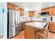 Well-lit kitchen with wooden cabinets, stainless steel appliances, and an island with seating at 4163 S Decatur St, Englewood, CO 80110