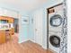 Hallway laundry with stackable washer and dryer in closet with blue curtain and hardwood floors, light blue walls at 4163 S Decatur St, Englewood, CO 80110