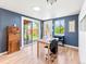 Brightly lit home office with a wooden desk, rolling chair, and a sliding glass door leading to backyard at 4163 S Decatur St, Englewood, CO 80110
