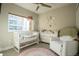 A well-lit Bedroom featuring a white crib, comfortable armchair, and charming decor under a ceiling fan at 2870 W Parkside Pl, Denver, CO 80221