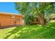 Brick home exterior and grassy backyard with mature shade tree creating dappled sunlight at 2682 S Benton St, Lakewood, CO 80227