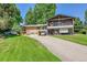 Spacious home with a long driveway, two-car garage, mature trees, and lush green lawn at 2682 S Benton St, Lakewood, CO 80227