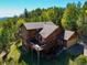 Expansive aerial view of log cabin featuring a deck, surrounded by lush trees, with a mountain backdrop at 10333 Georgia Cir, Morrison, CO 80465