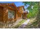 Beautiful wood cabin with stone accents, large windows, and a sidewalk, surrounded by a lush forest at 10333 Georgia Cir, Morrison, CO 80465
